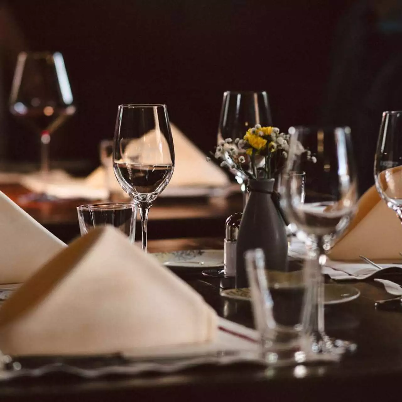 Vier vrienden proosten met rode wijn in een gezellig verlichte, met hout beklede gelagkamer.